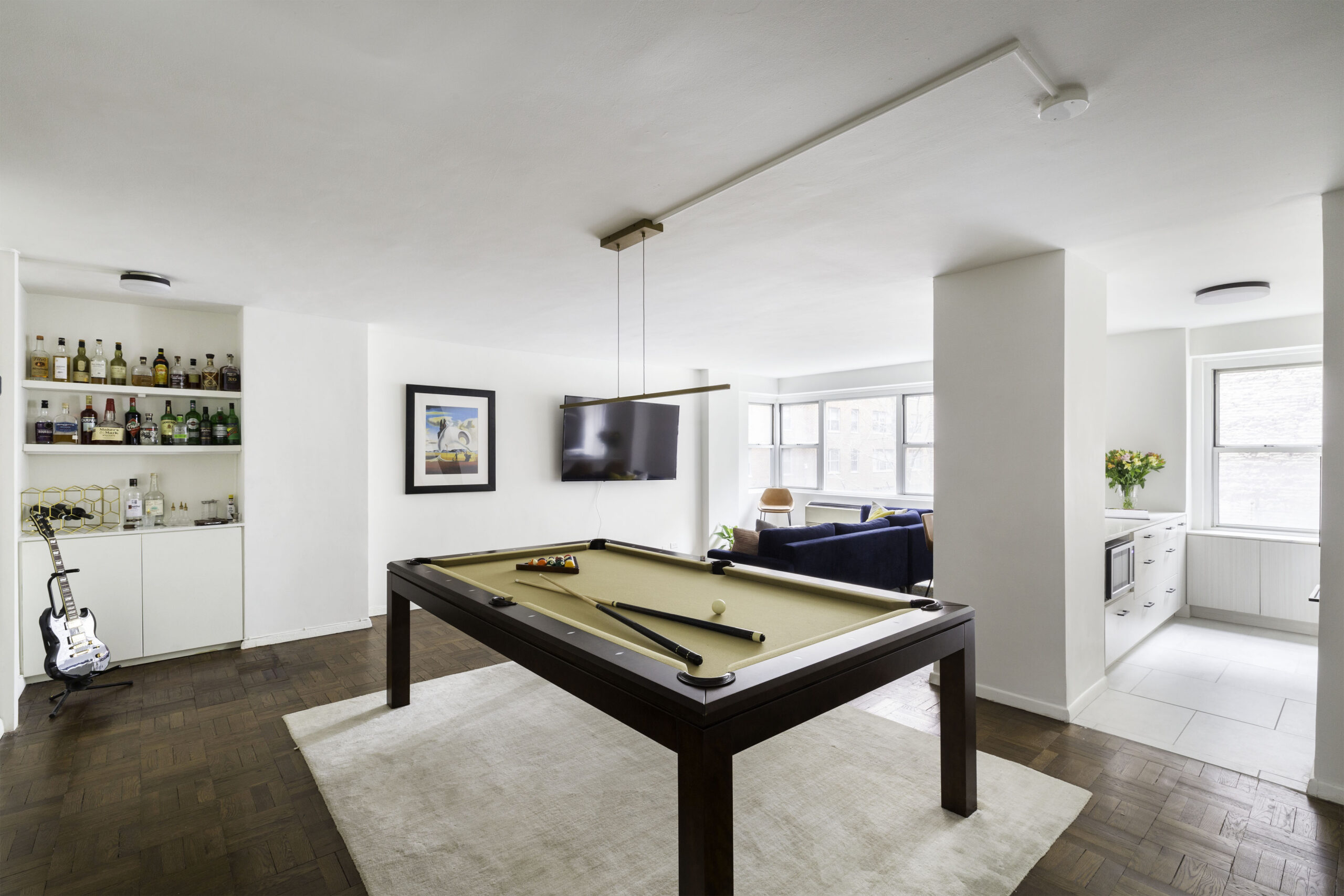 Living room with pool table in the middle, hanging light, and a dry bar at the corner