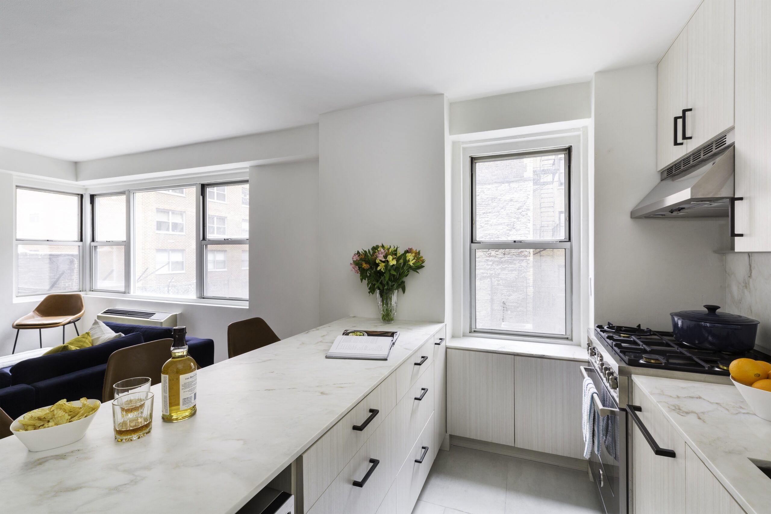Kitchen with Calacatta marble counter with white cabinetry and open windows