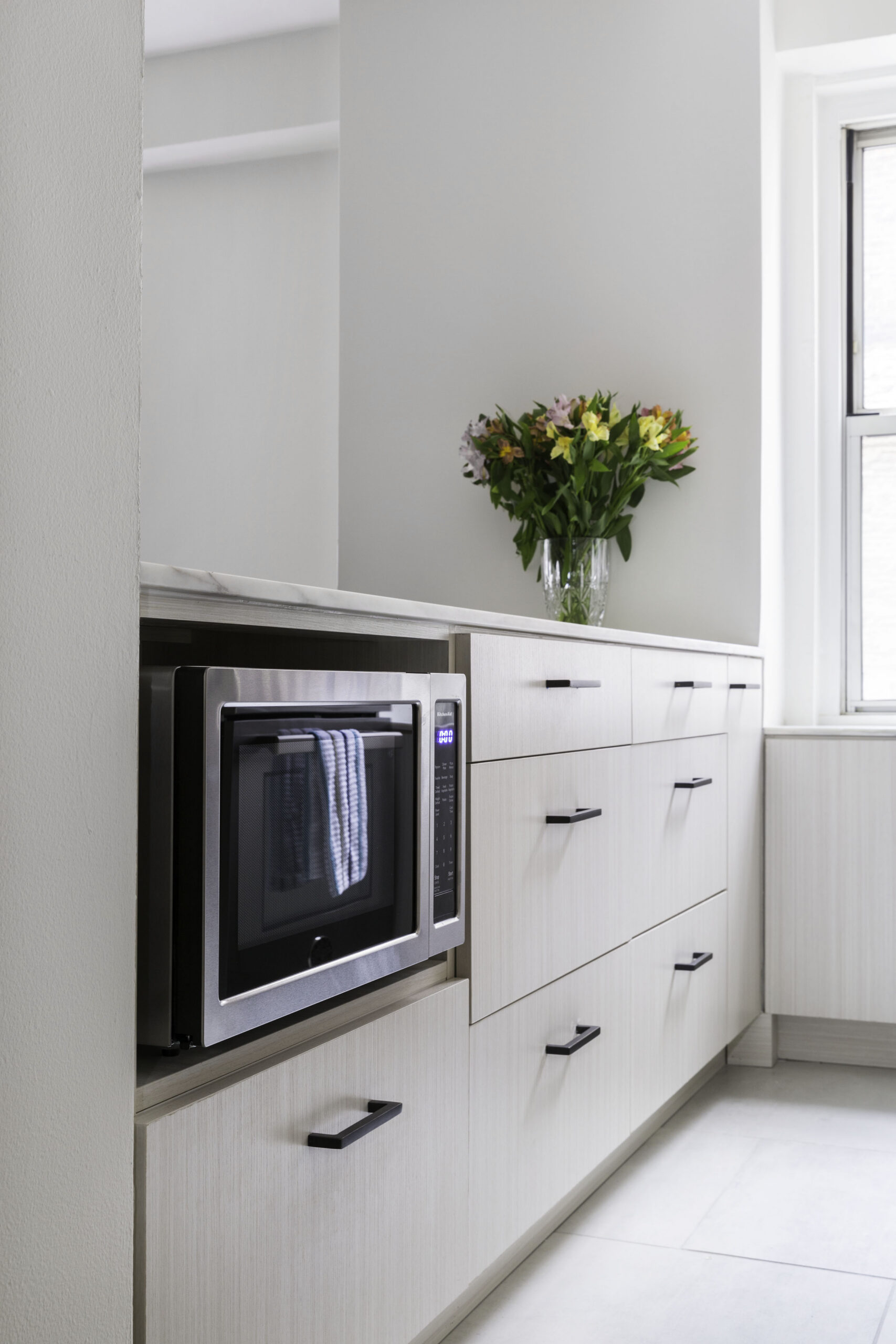 Kitchen peninsula with built-in microwave oven, drawers, and a bouquet of flowers