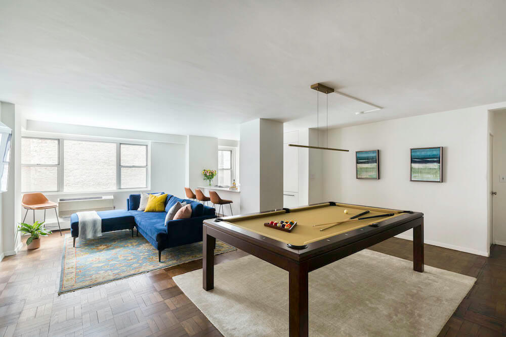 A bachelor pad renovation featuring a billiard pool table in living room with blue couch