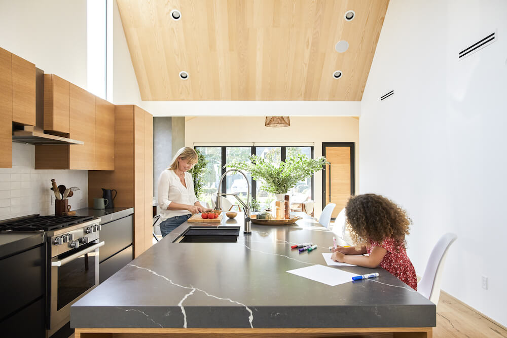 Candid photo of mom and daughter hanging out at the kitchen island in their renovated Scandi-modern LA home